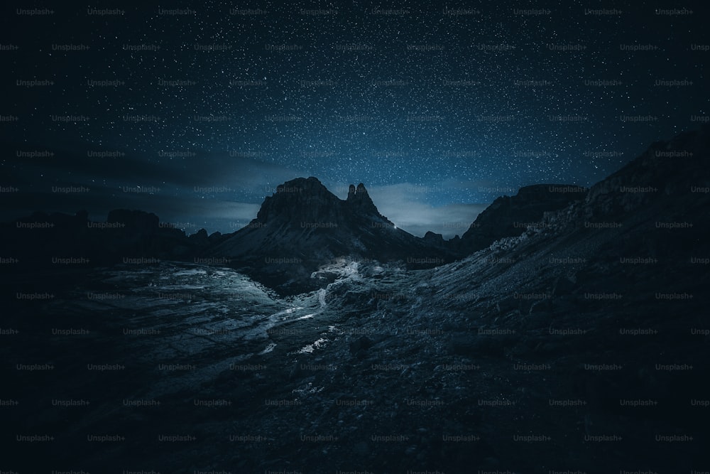 a night sky with stars above a mountain