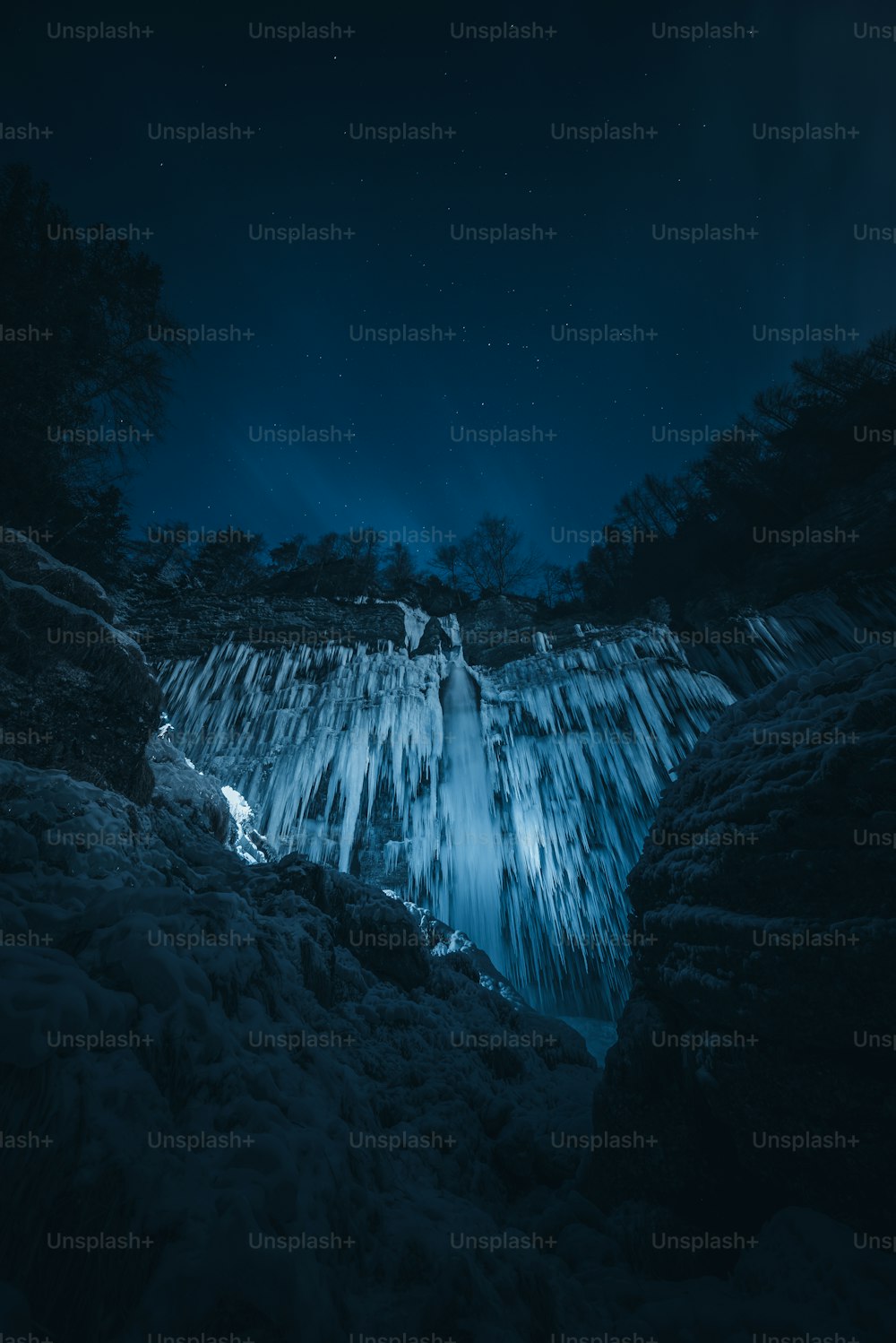 a frozen waterfall in the middle of a forest at night