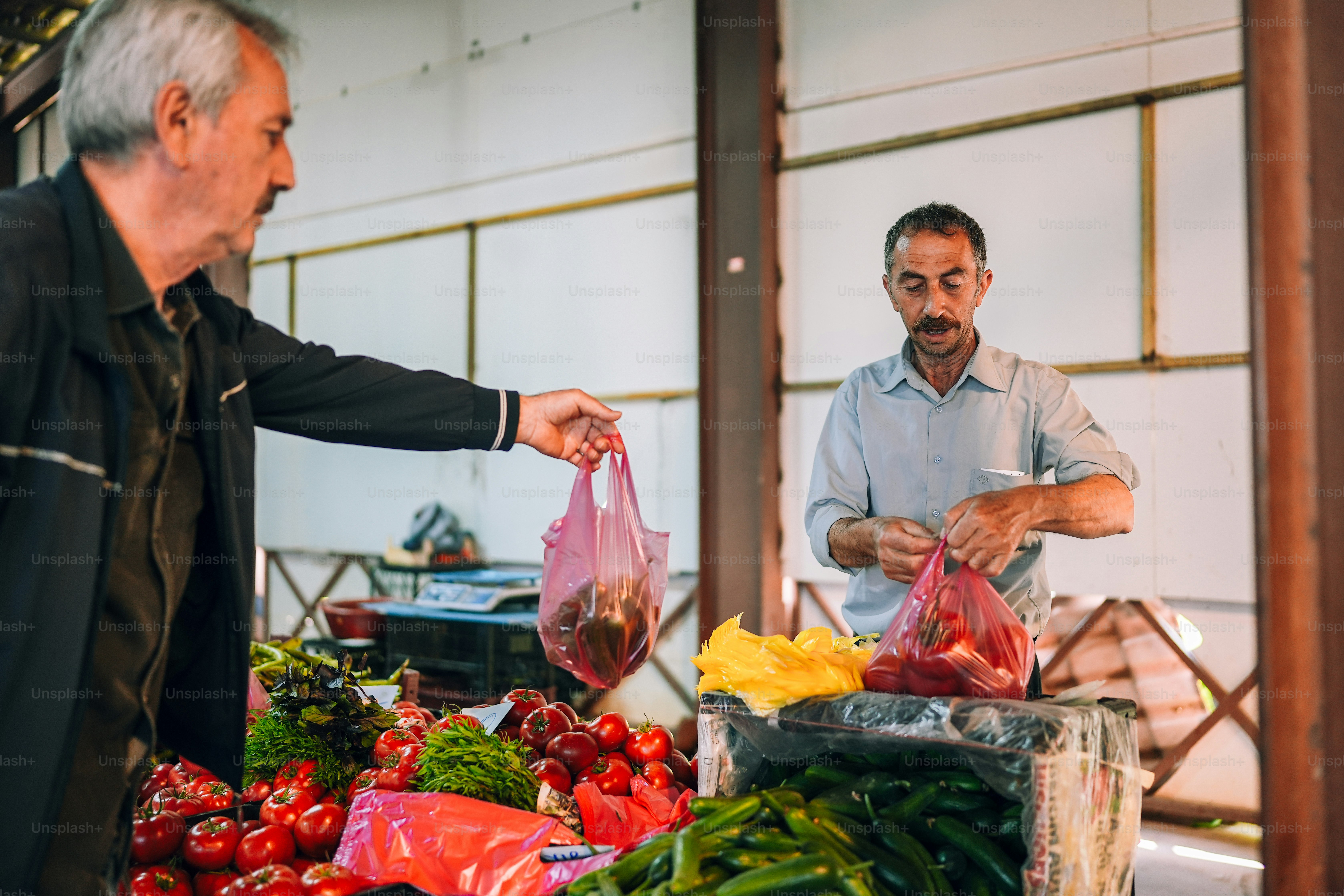 Un couple d’hommes debout à côté d’un tas de légumes