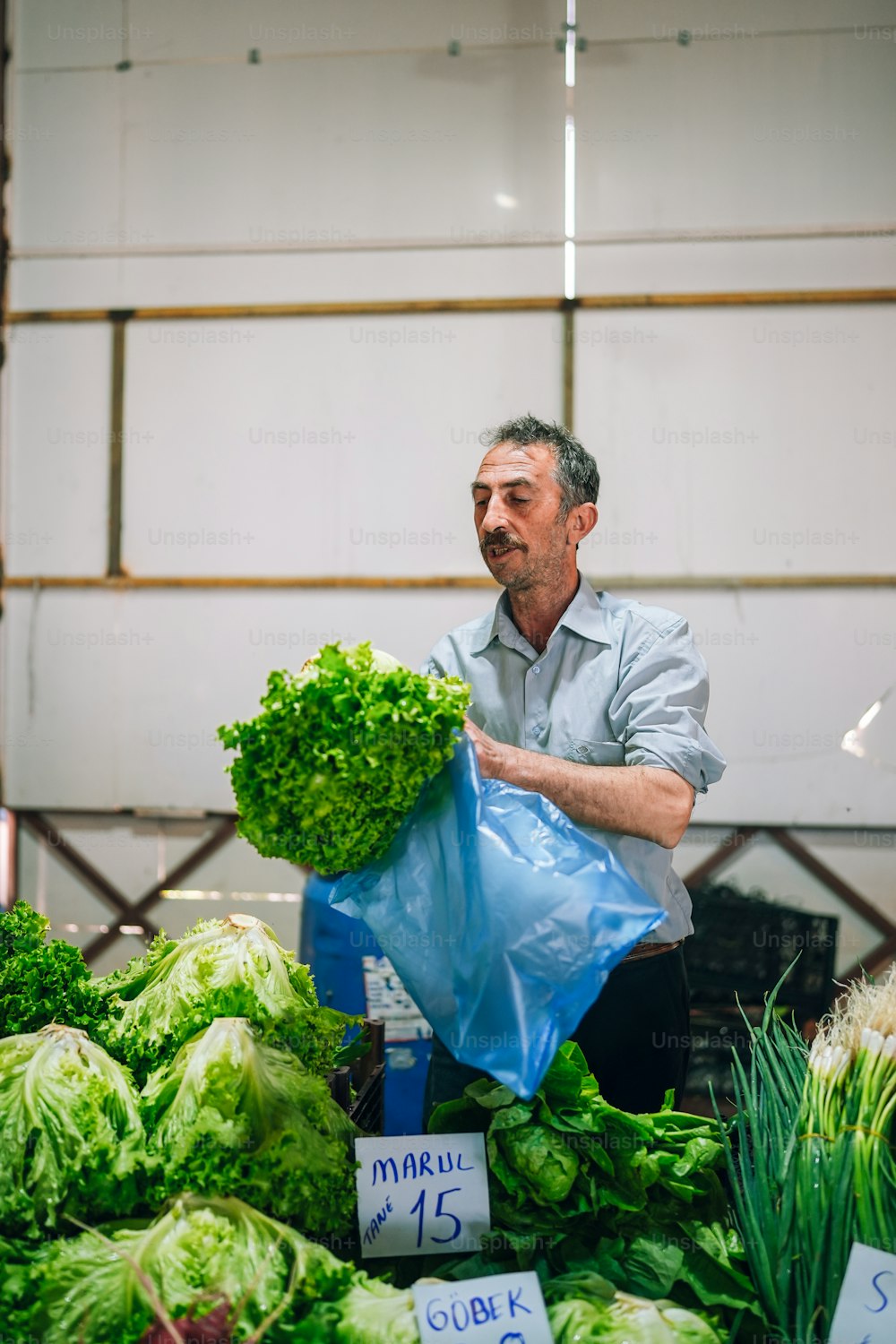 a man holding a bag of lettuce at a market
