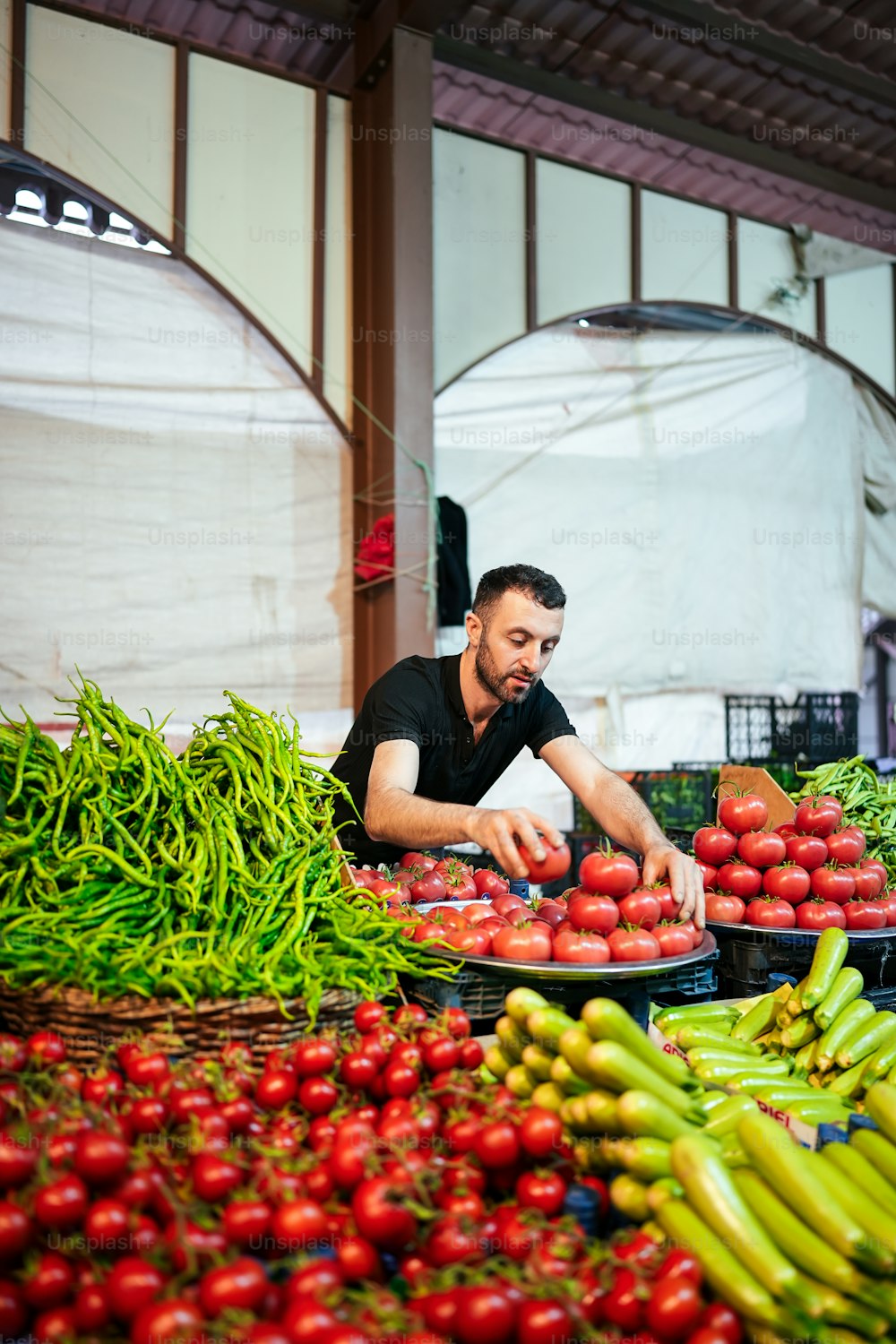 Un uomo in piedi davanti a un'esposizione di frutta e verdura