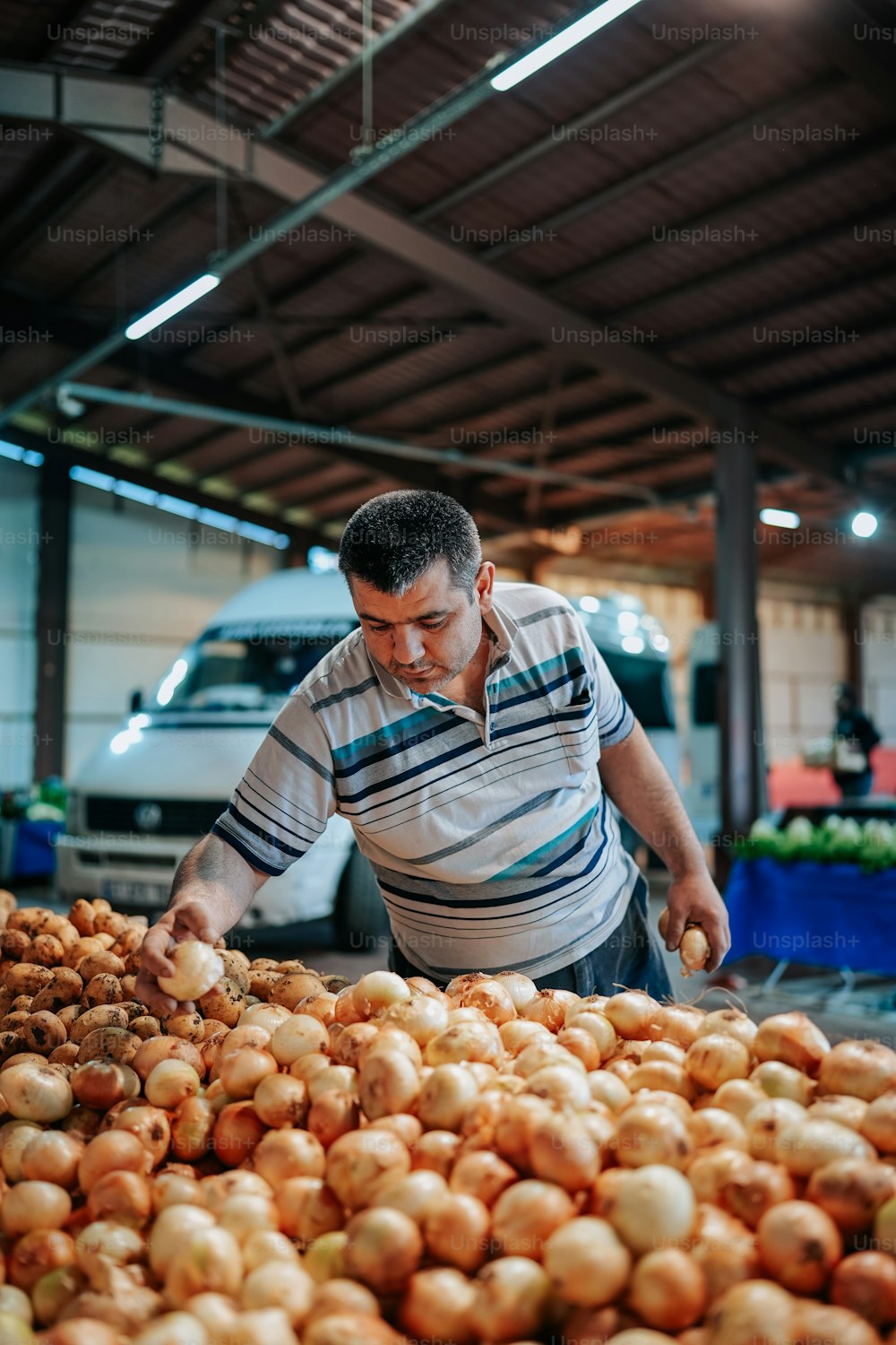 a man standing over a pile of onions
