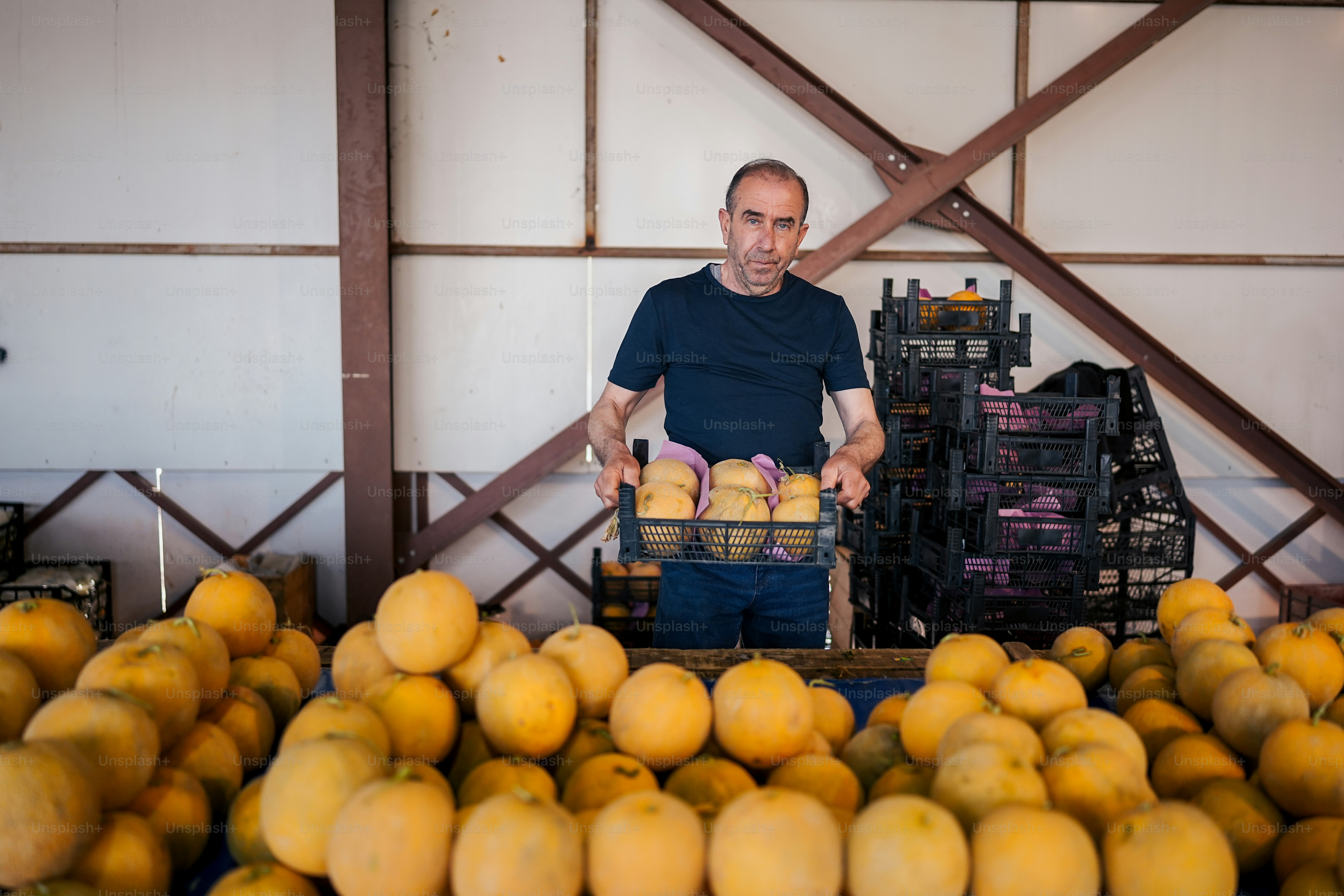 a man standing in front of a pile of oranges