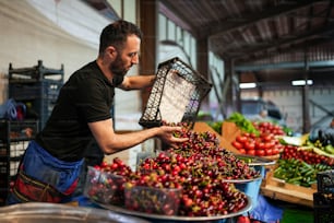 a man holding a basket of cherries in a market