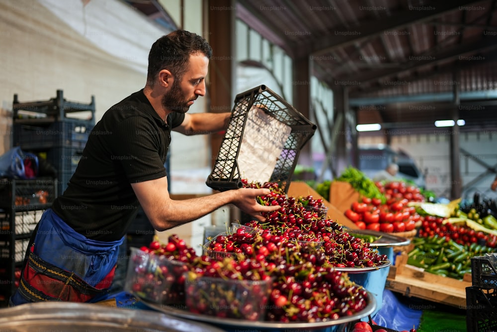 a man holding a basket of cherries in a market