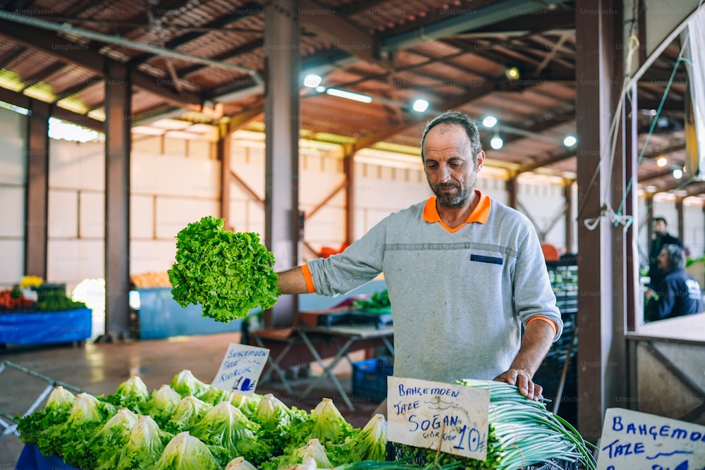 Un hombre parado frente a una mesa llena de verduras
