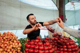 a man handing a bag of tomatoes to another man