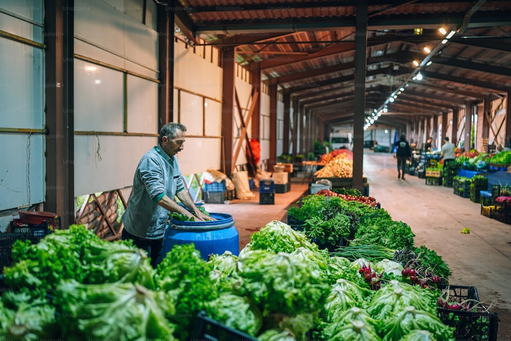 Un uomo in piedi in un magazzino pieno di un sacco di verdure