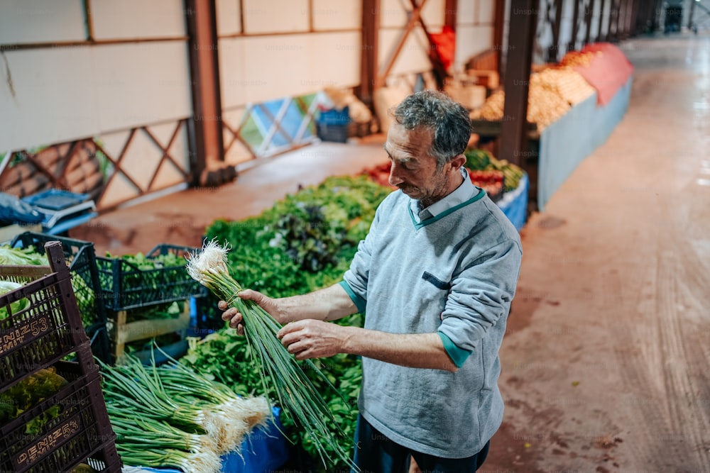 Un uomo in piedi davanti a un mucchio di verdure