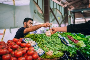 a man standing in front of a pile of vegetables