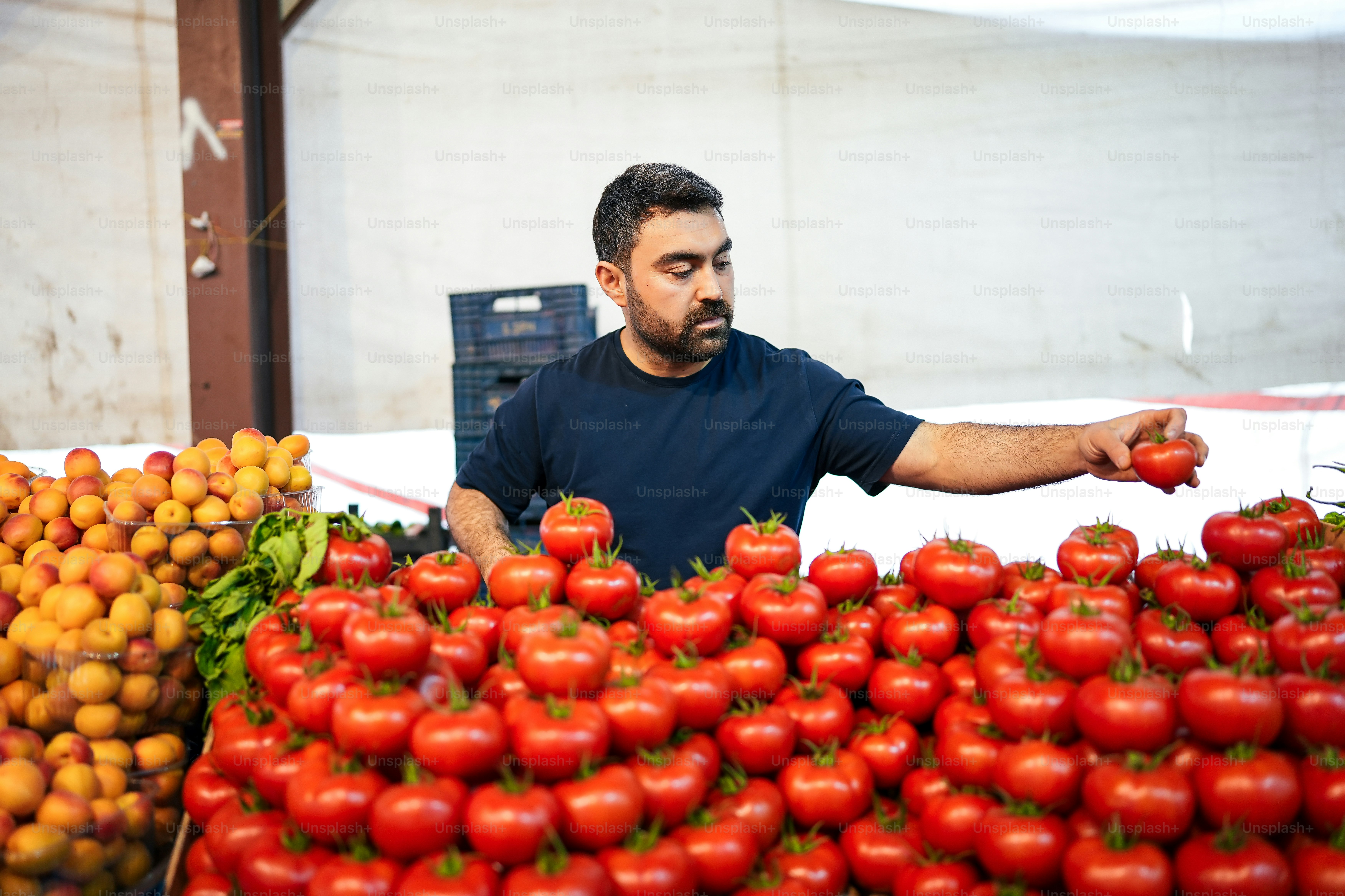 a man standing in front of a pile of tomatoes