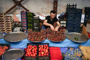 a man standing over a table filled with lots of fruit
