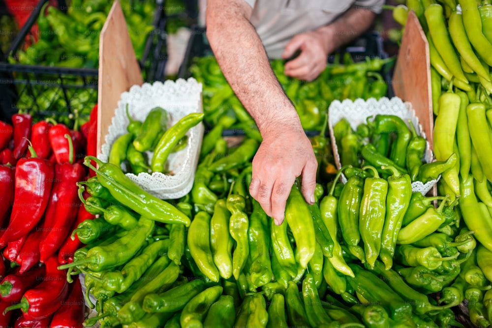 a person reaching for peppers at a market