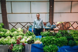 a man standing in front of a bunch of vegetables