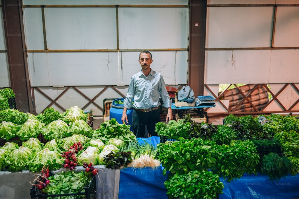 Un uomo in piedi davanti a un mazzo di verdure