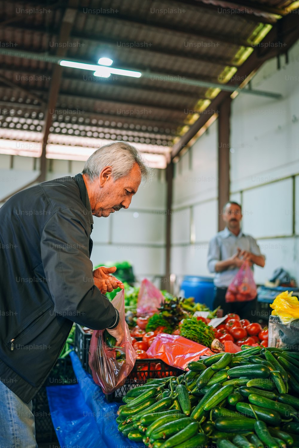 Un hombre parado frente a una pila de verduras