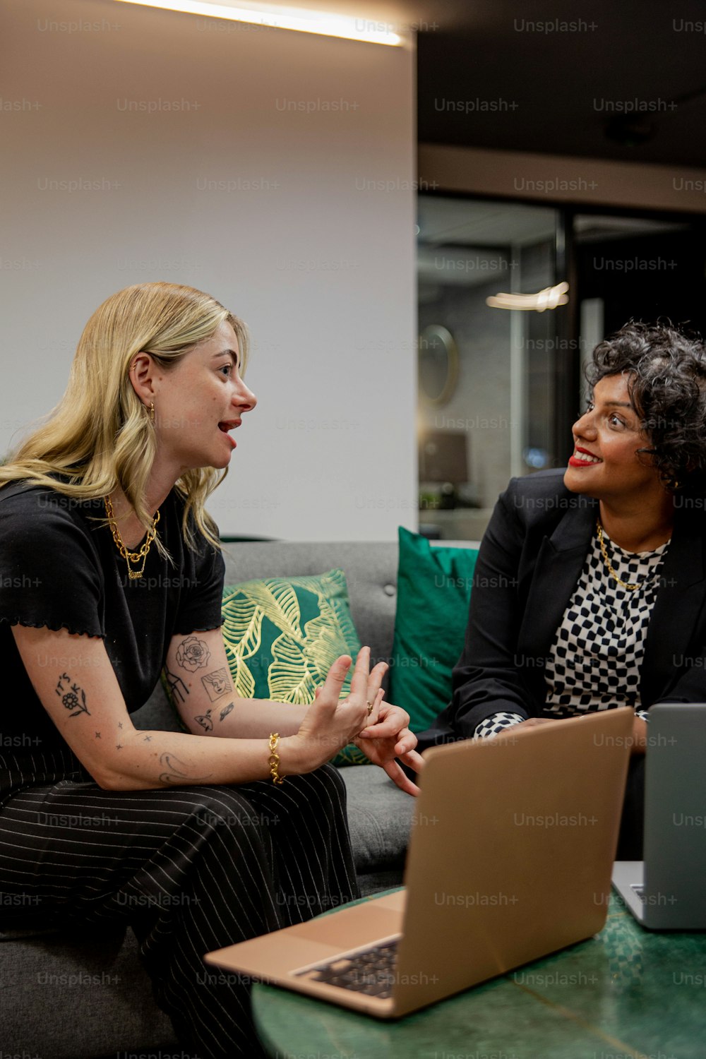 a woman sitting on a couch talking to another woman