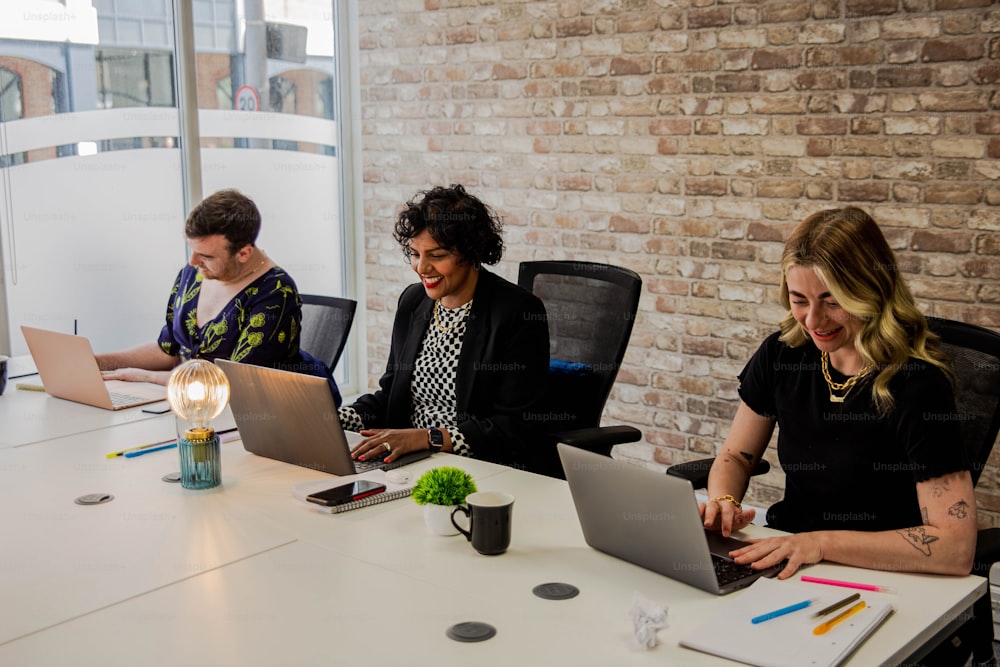 a group of people sitting around a table working on laptops