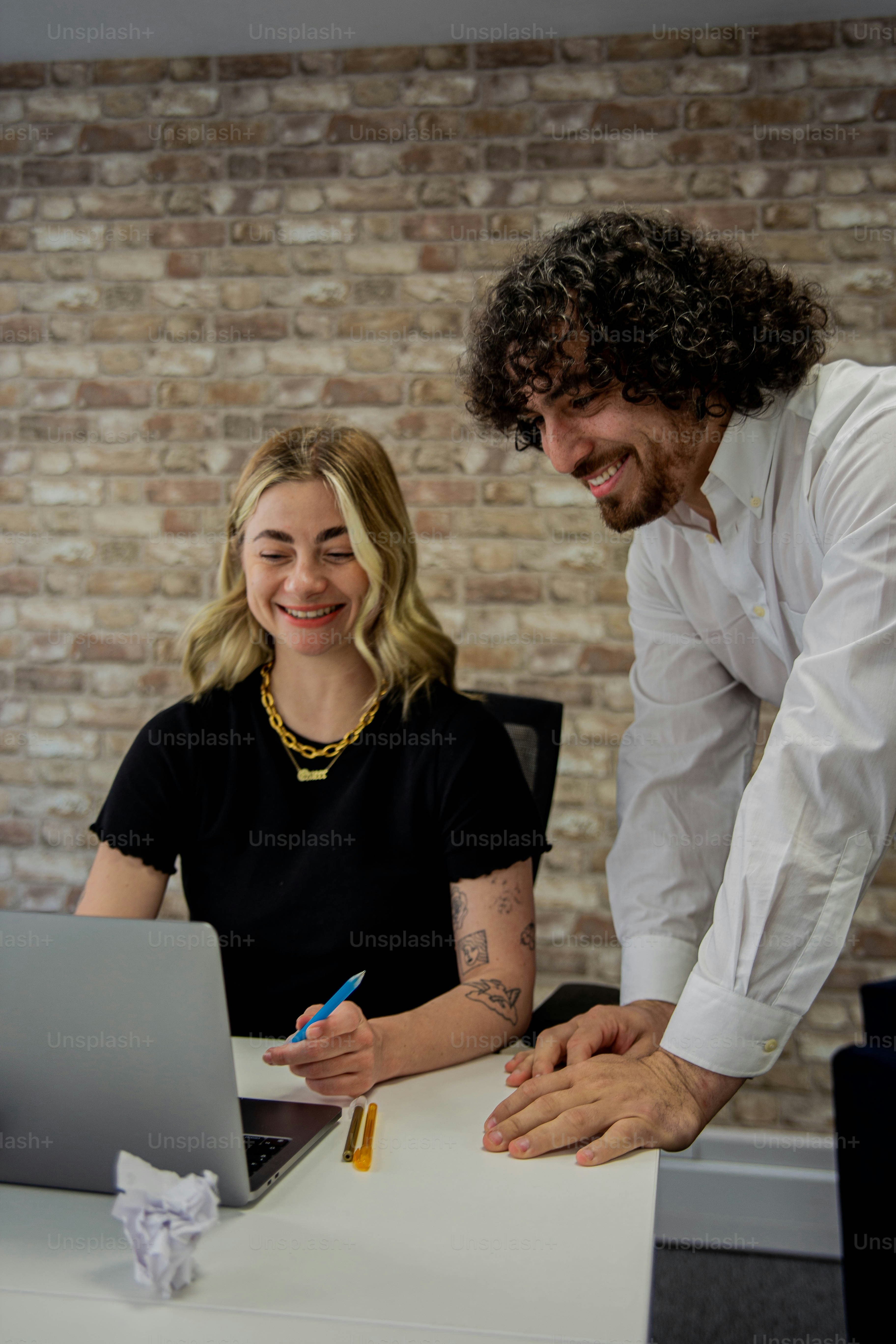 um homem e uma mulher sentados em uma mesa com um laptop