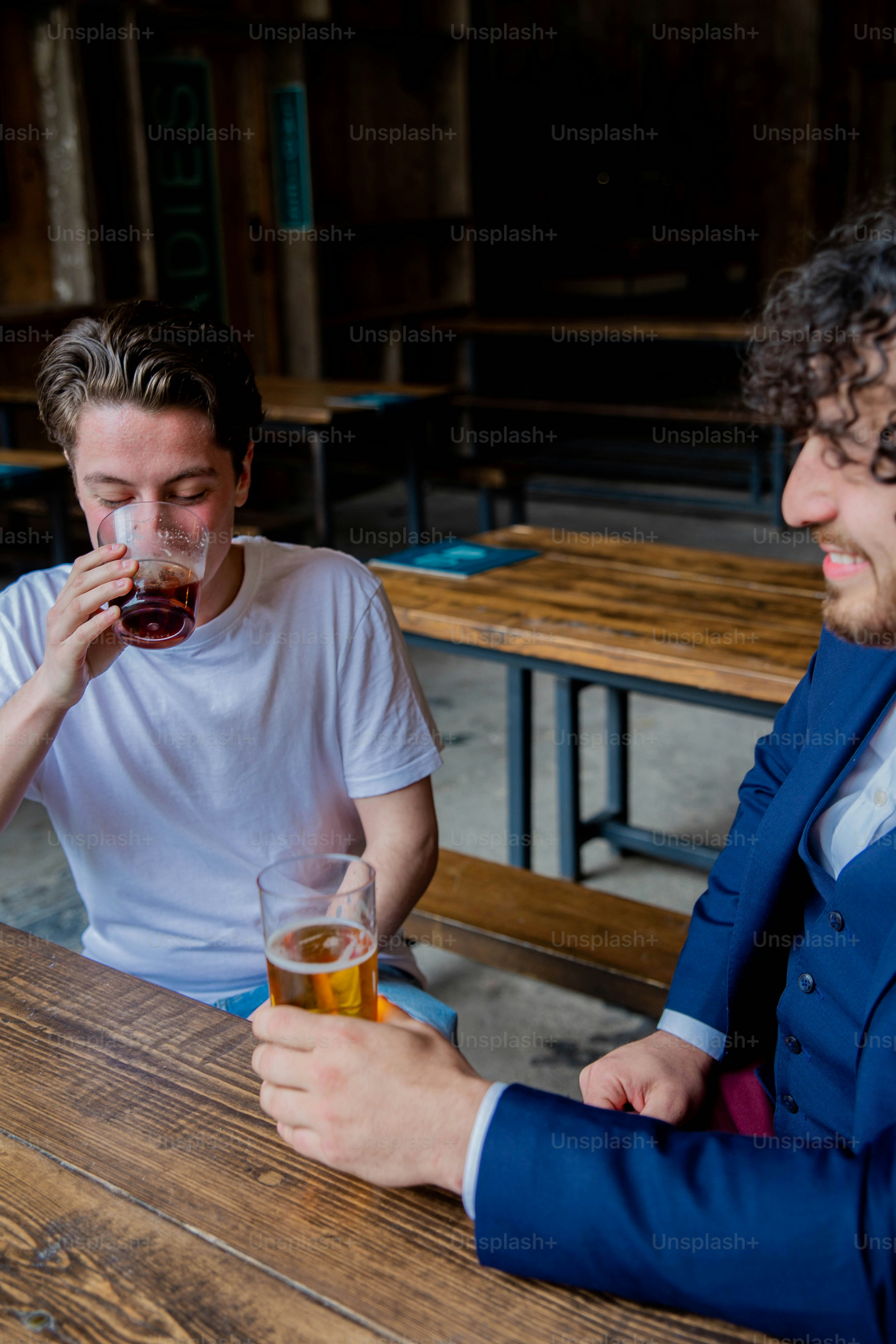 two men sitting at a table drinking beer
