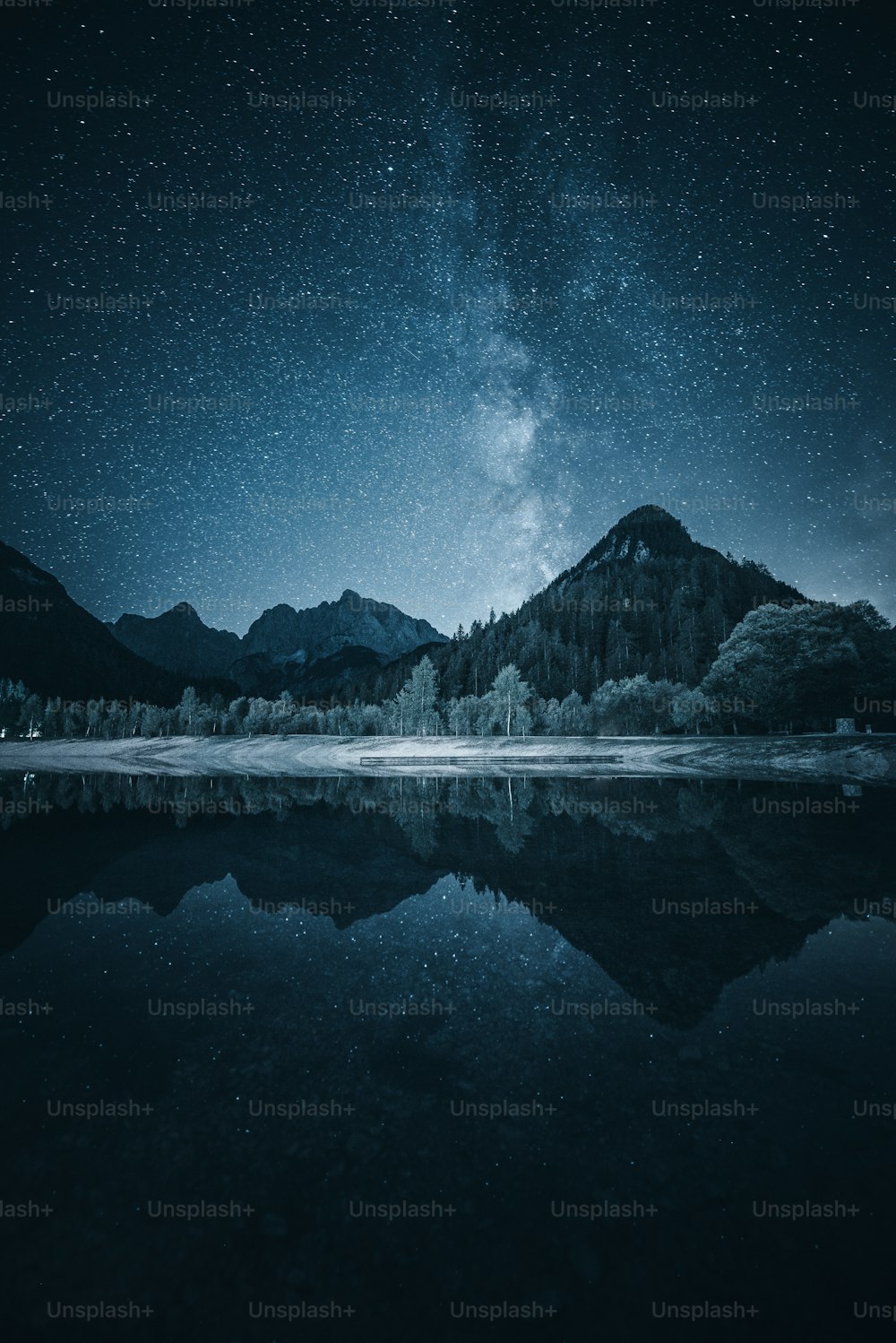 O céu noturno é refletido na água parada de um lago