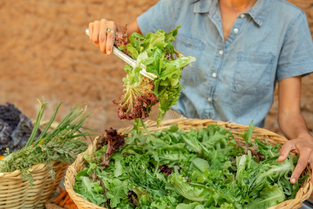 a woman is holding a basket full of greens