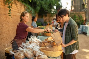 a woman handing a bag of bread to a man
