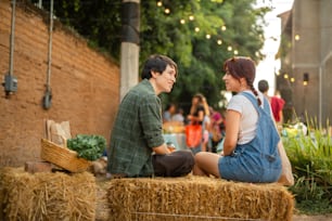 a man and woman sitting on hay bales talking