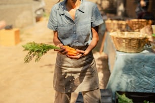 a woman holding a bunch of carrots in her hands