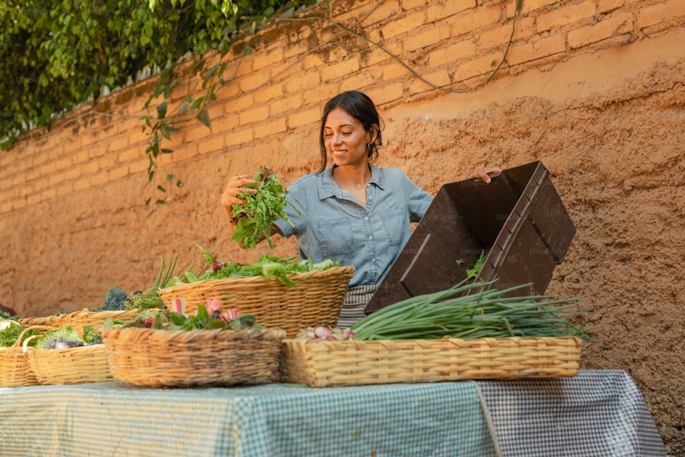 Une femme debout à côté d’une table remplie de paniers de légumes