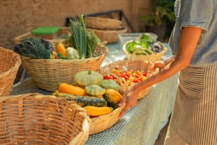 a woman standing next to a table filled with baskets of vegetables