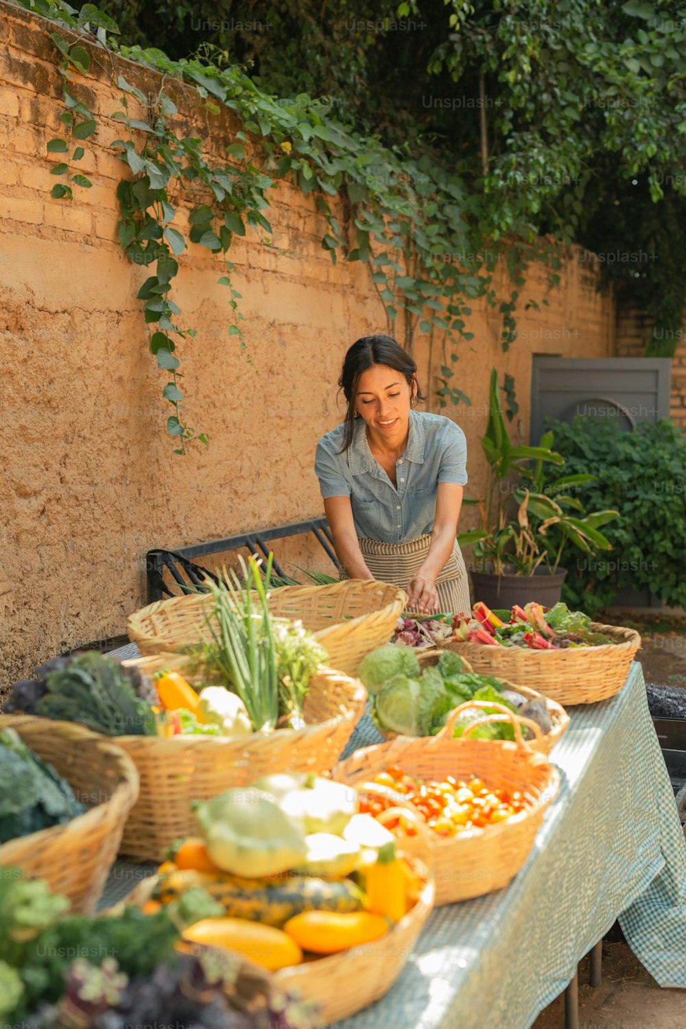 a woman sitting at a table filled with lots of vegetables