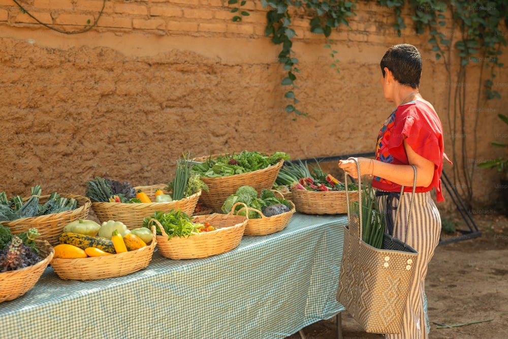 Un ragazzo in piedi davanti a un tavolo pieno di cesti di verdure