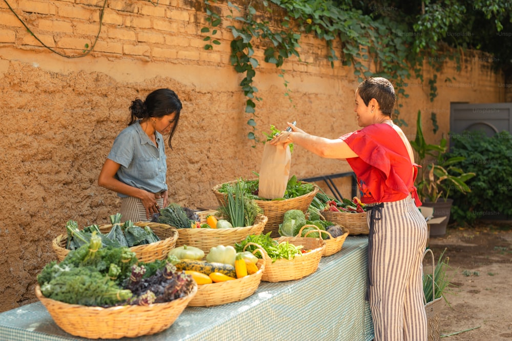 a woman standing next to a table filled with vegetables