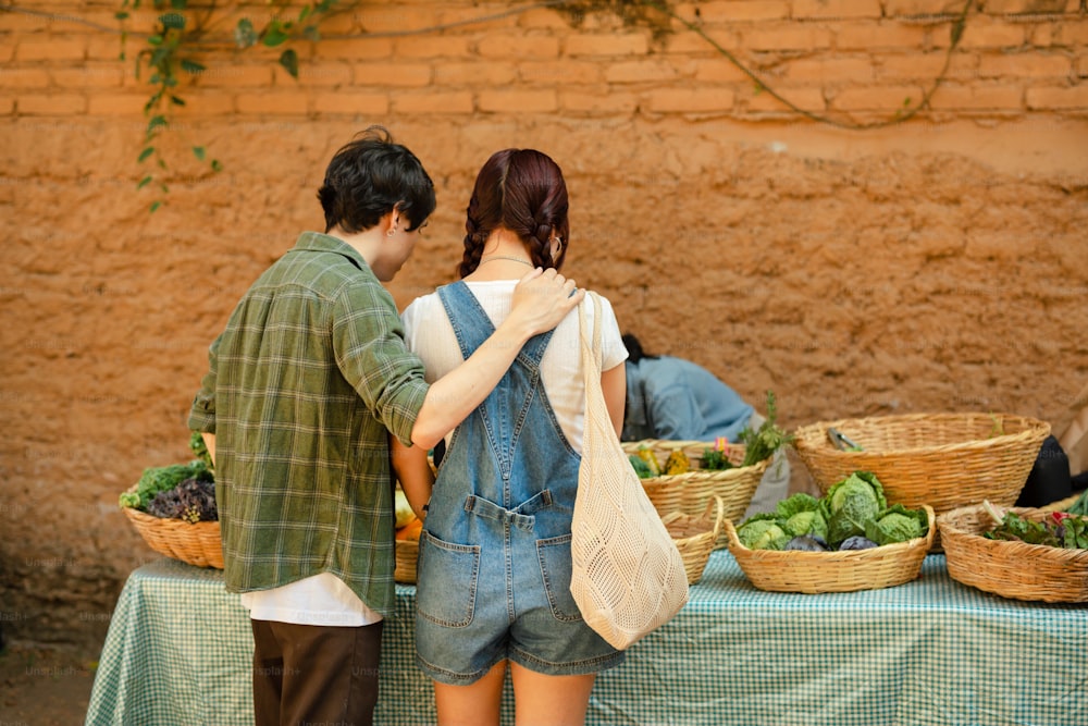 a man and a woman standing in front of a table full of vegetables