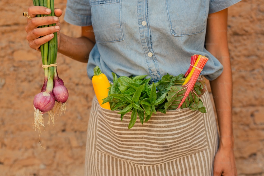 Una persona sosteniendo un manojo de verduras en sus manos