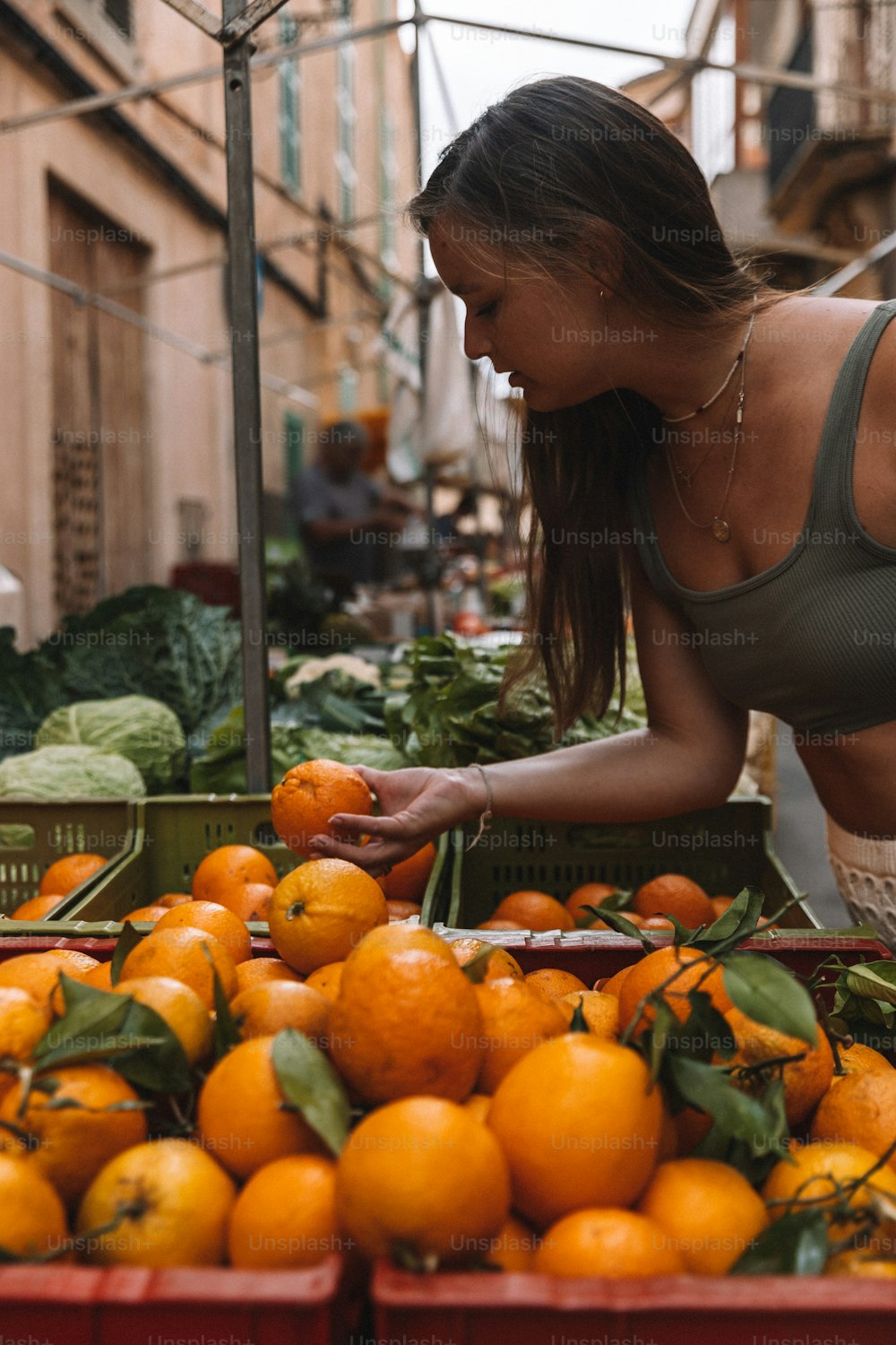 a woman in a green tank top picking up oranges