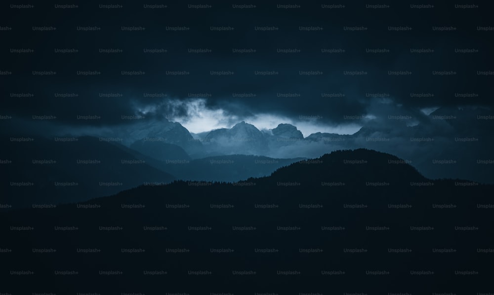 Une chaîne de montagnes avec un ciel sombre en arrière-plan