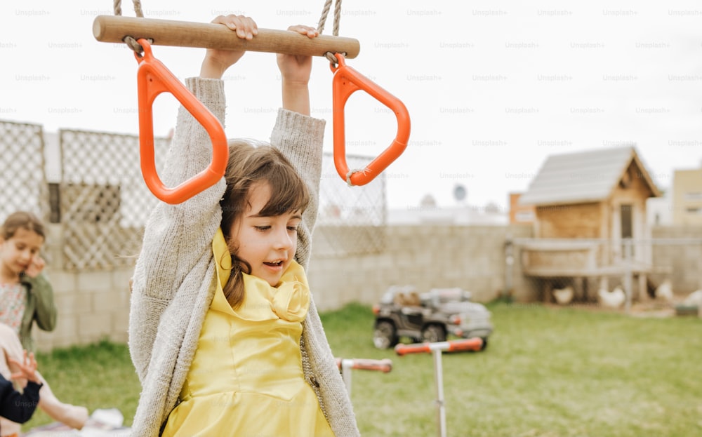 a little girl in a yellow dress on a swing