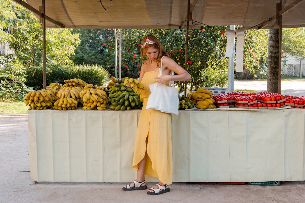 a woman standing in front of a fruit stand