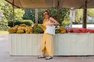 a woman standing in front of a fruit stand