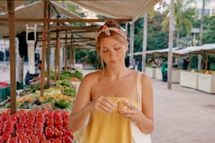 a woman standing in front of a fruit stand