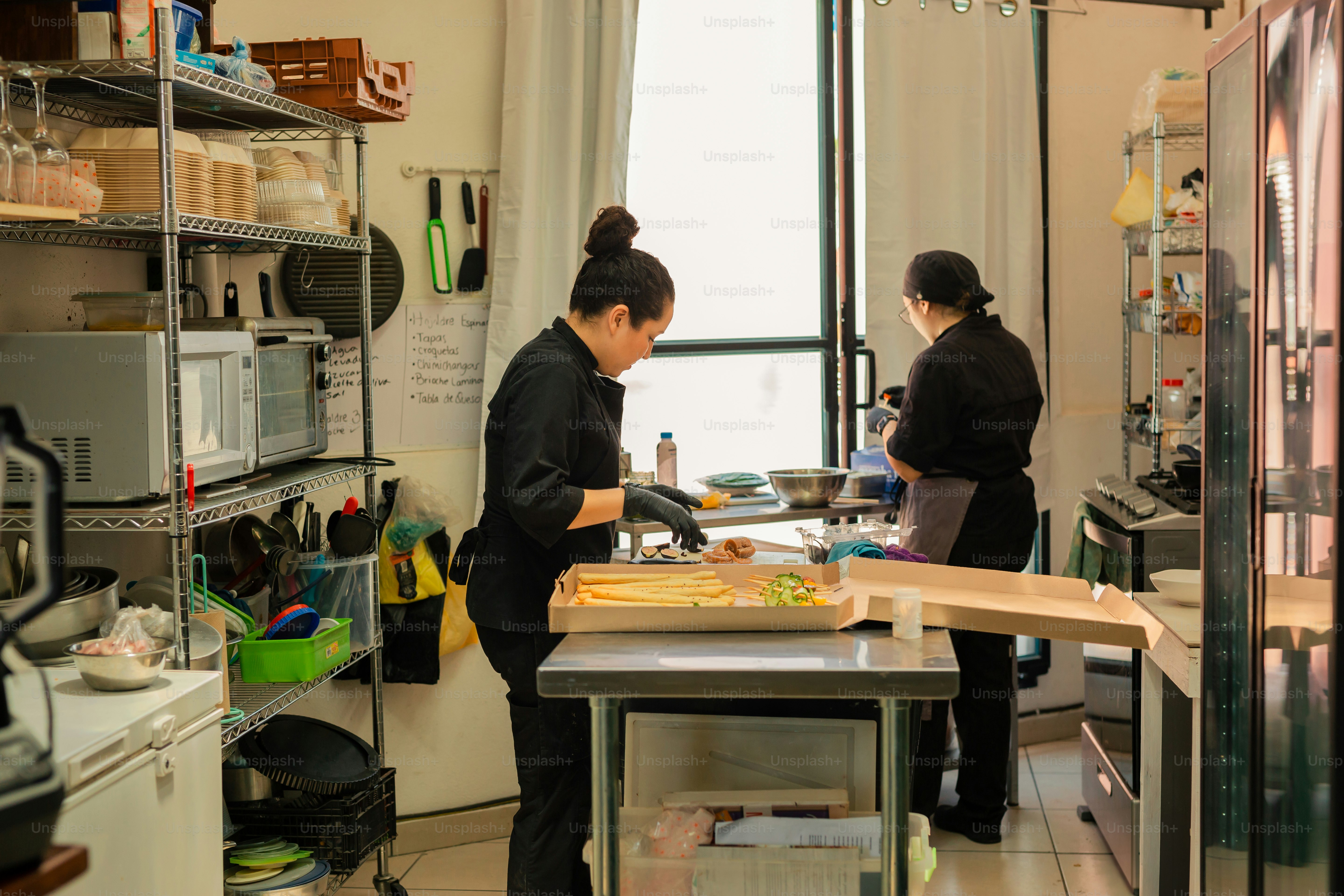 a couple of women standing in a kitchen preparing food