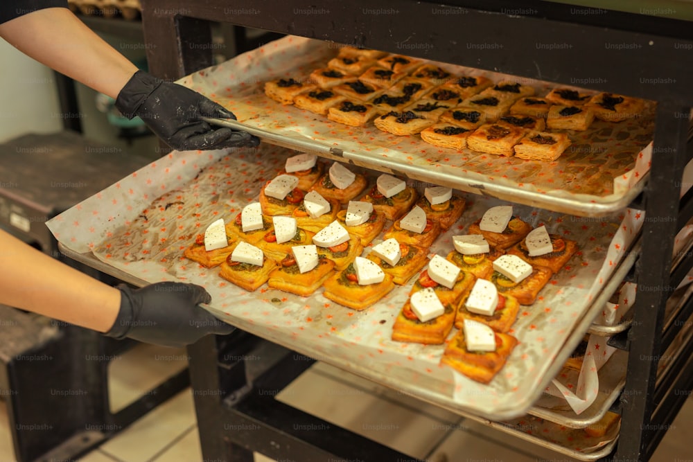 a person in black gloves putting food on a tray