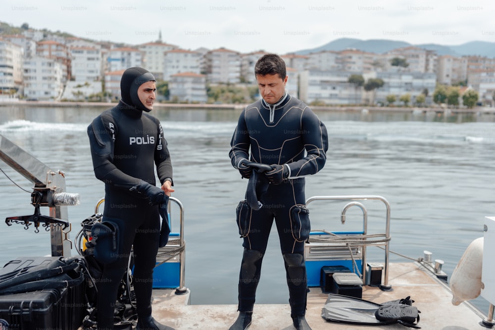two men in wet suits standing on a boat
