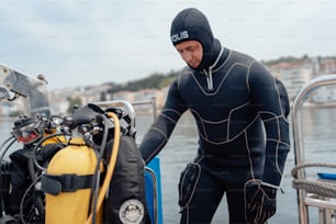 a man in a wet suit standing next to a diving equipment