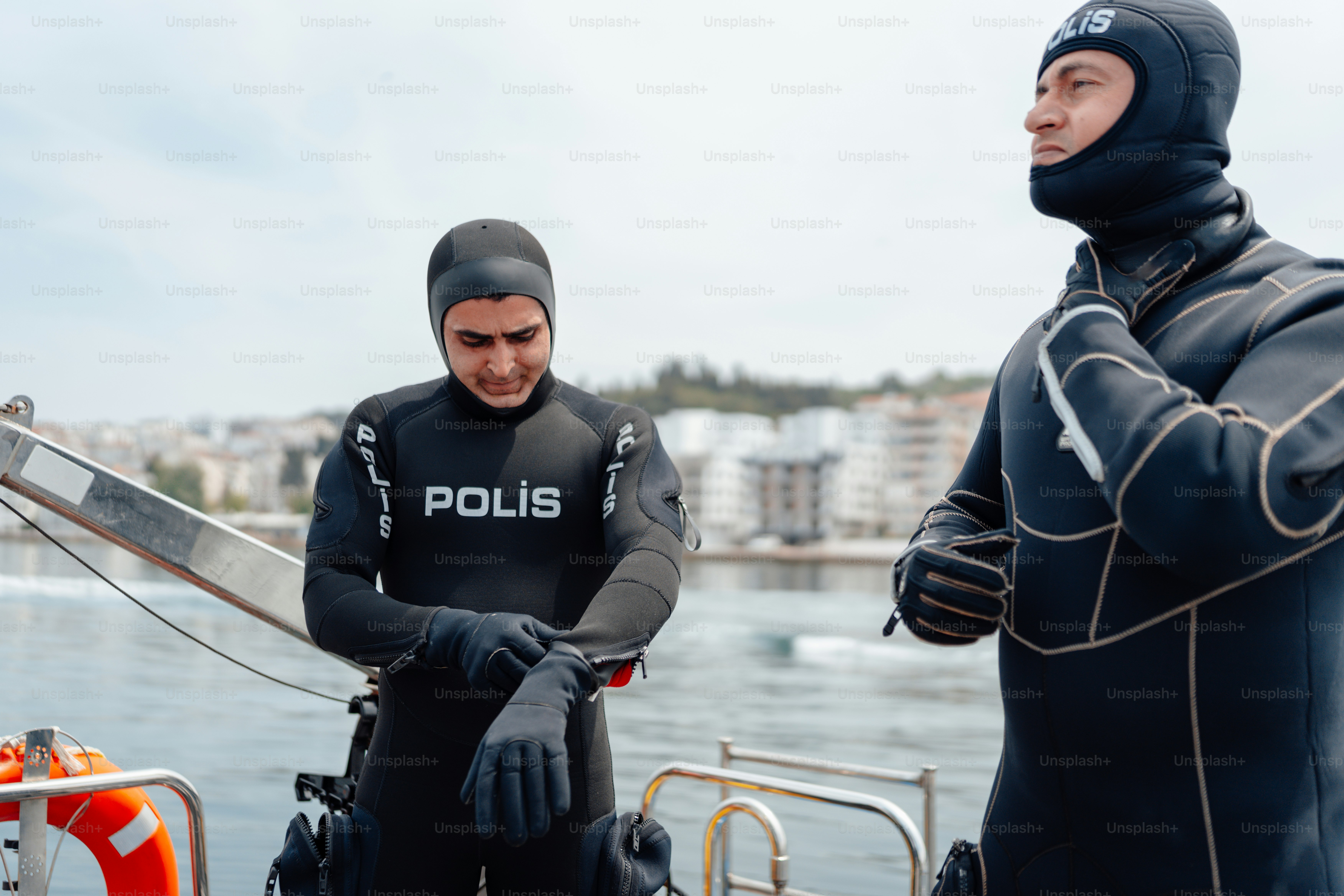 two men in wetsuits standing on a boat