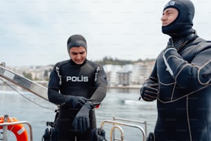 two men in wetsuits standing on a boat