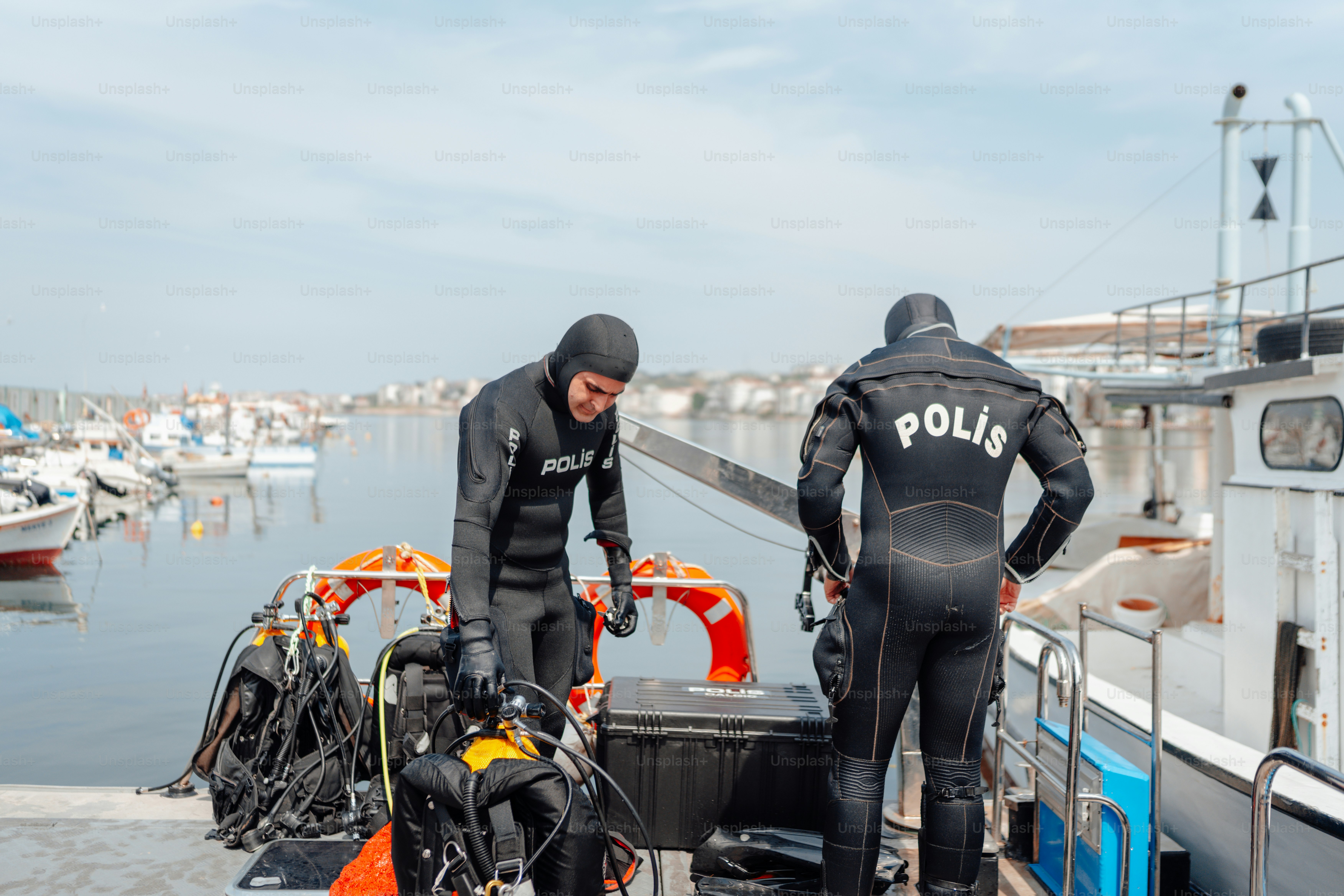 Un paio di uomini in muta in piedi accanto a una barca