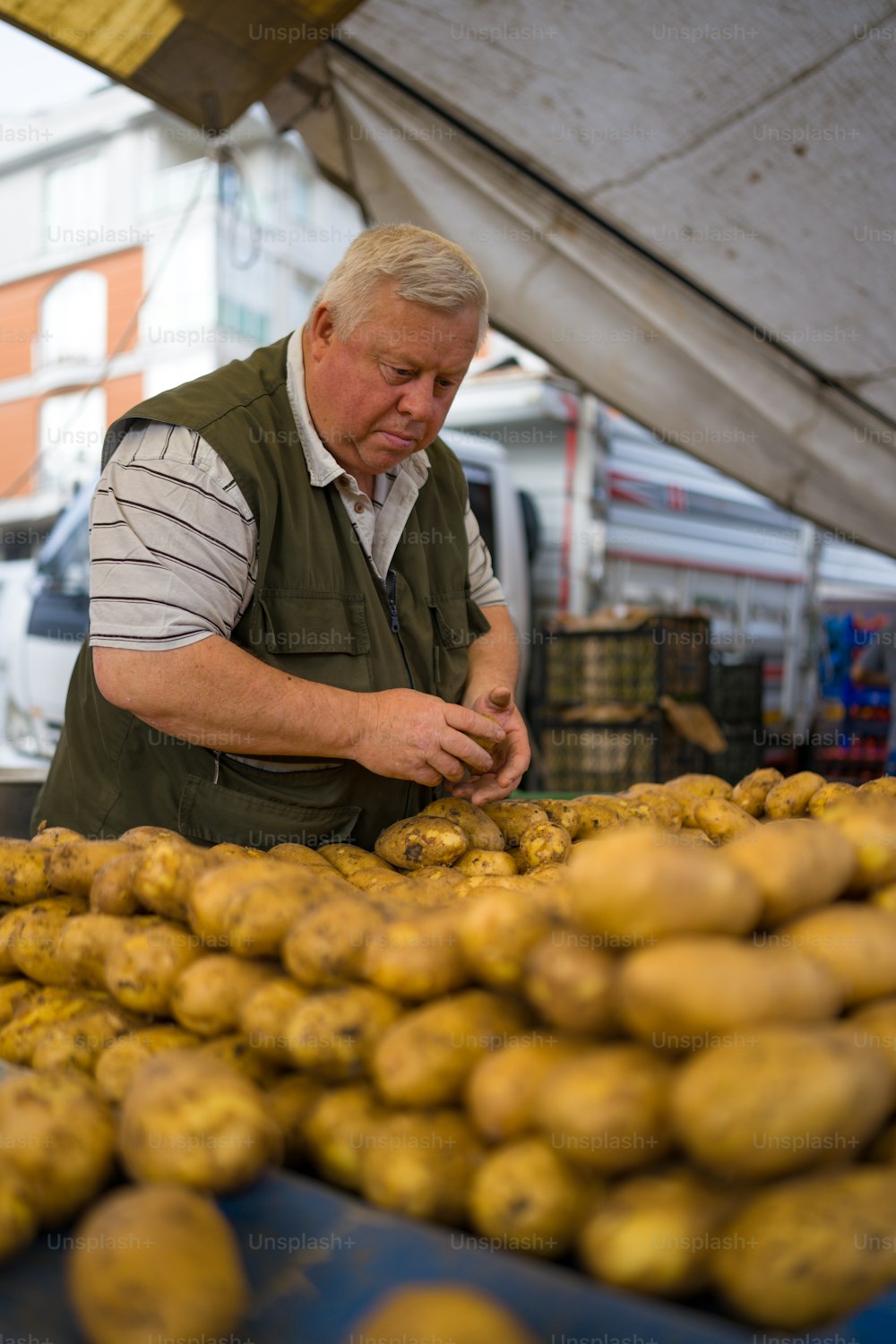 Un homme debout devant un tas de pommes de terre